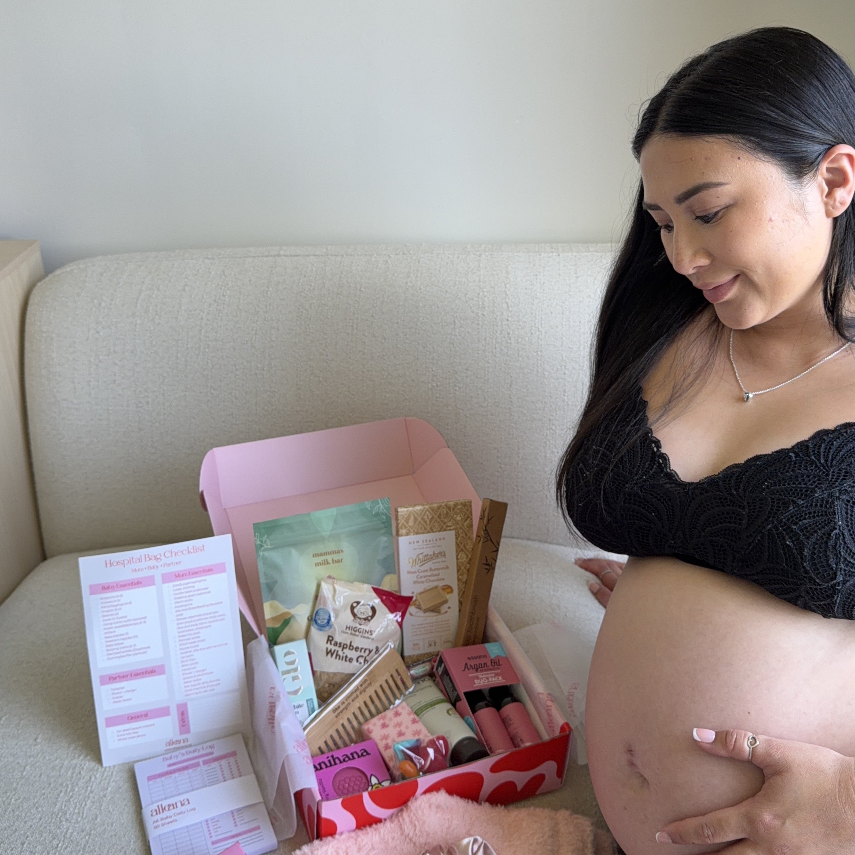 Pregnant woman looking at a box of products on a couch